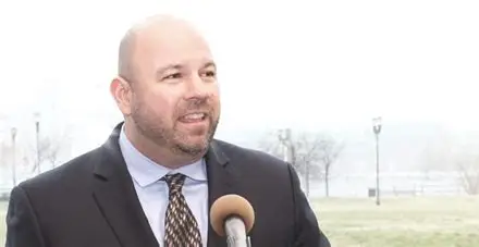 Ken Wisnefski speaking outdoors into a handheld microphone
