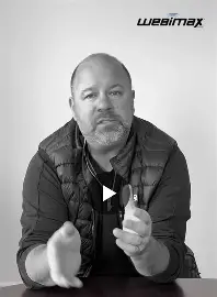 Black-and-white still of Ken Wisnefski speaking to camera with the WebiMax logo